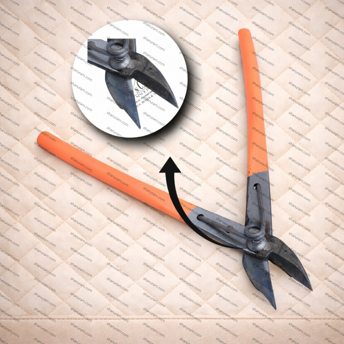 Orange and black archery broadhead on a textured surface with a close-up inset.